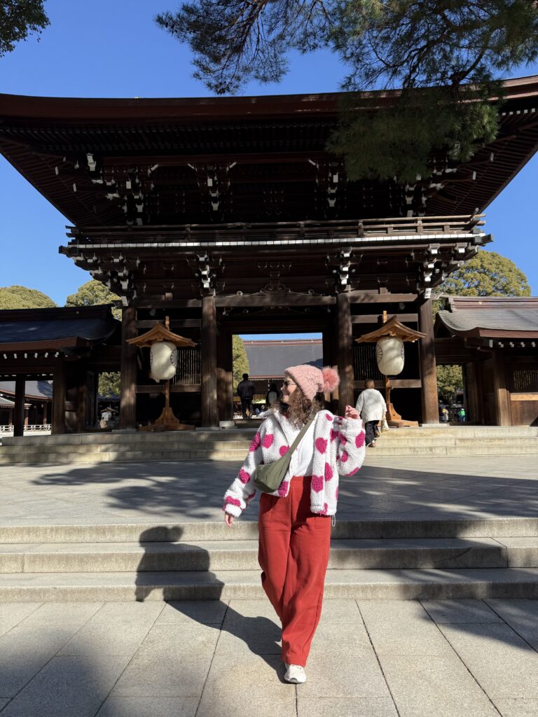 Mulher caminhando em frente ao portão de madeira Romon do Santuário Meiji, em Tóquio