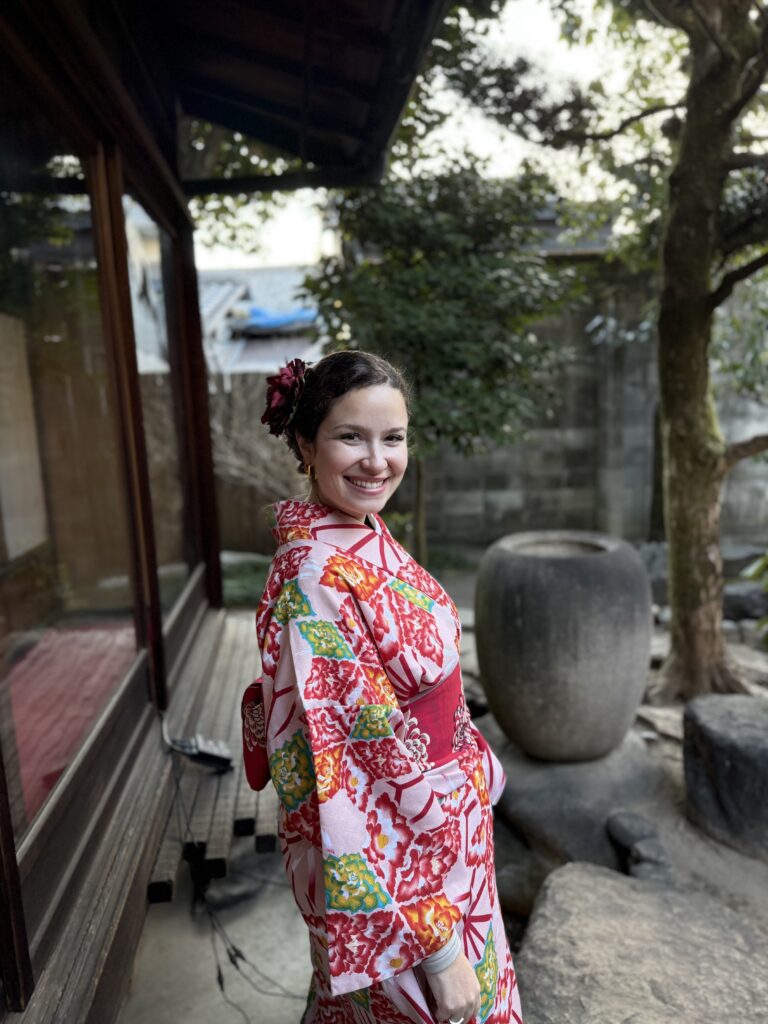 Mulher usando kimono estampado em vermelho e branco em um jardim tradicional, em Kyoto