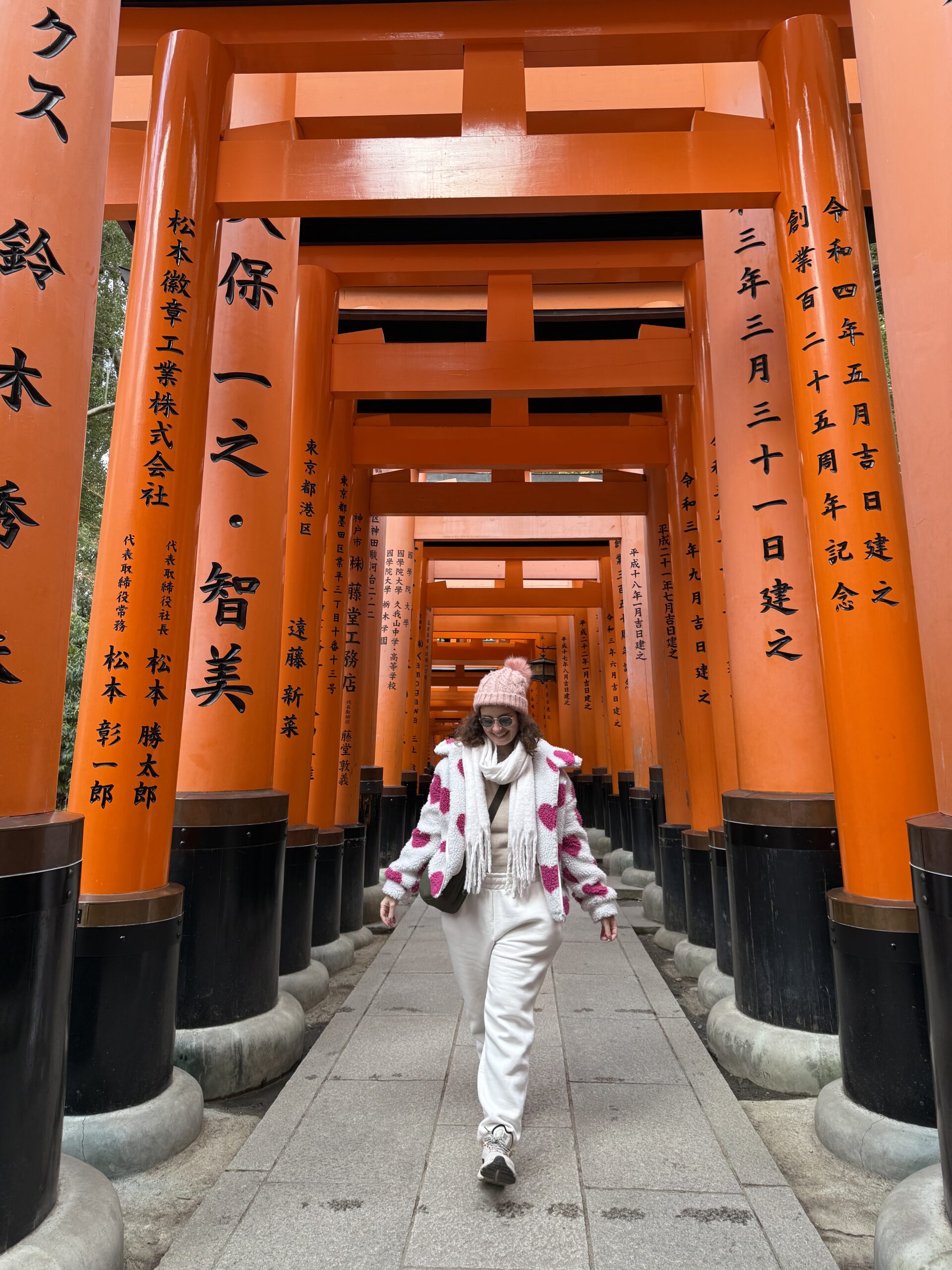 Mulher caminhando pelo túnel de portões torii laranja do Senbon Torii, no Fushimi Inari, em Kyoto