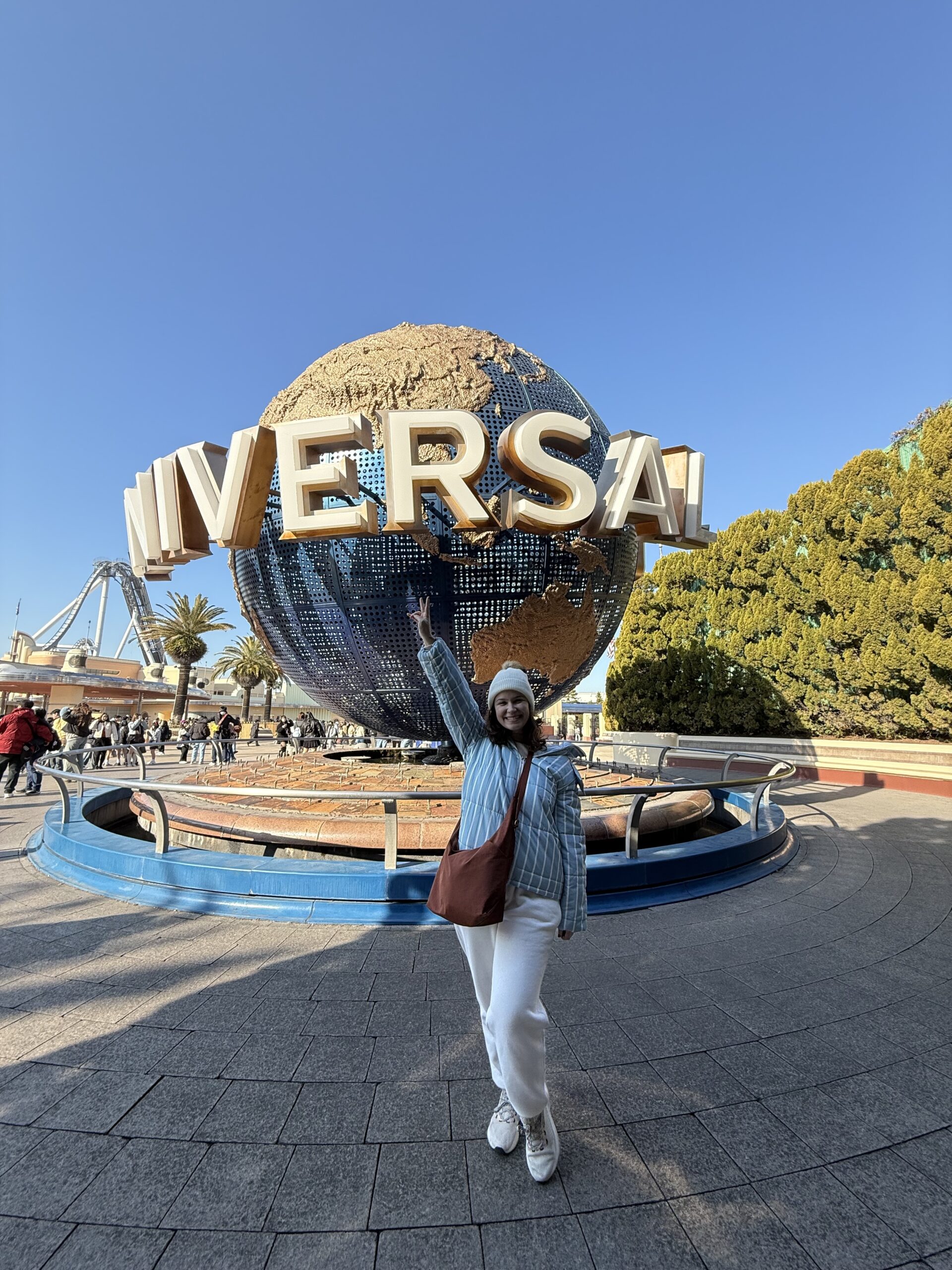 Mulher de braços abertos em frente ao globo giratório do Universal Studios Japan, em Osaka
