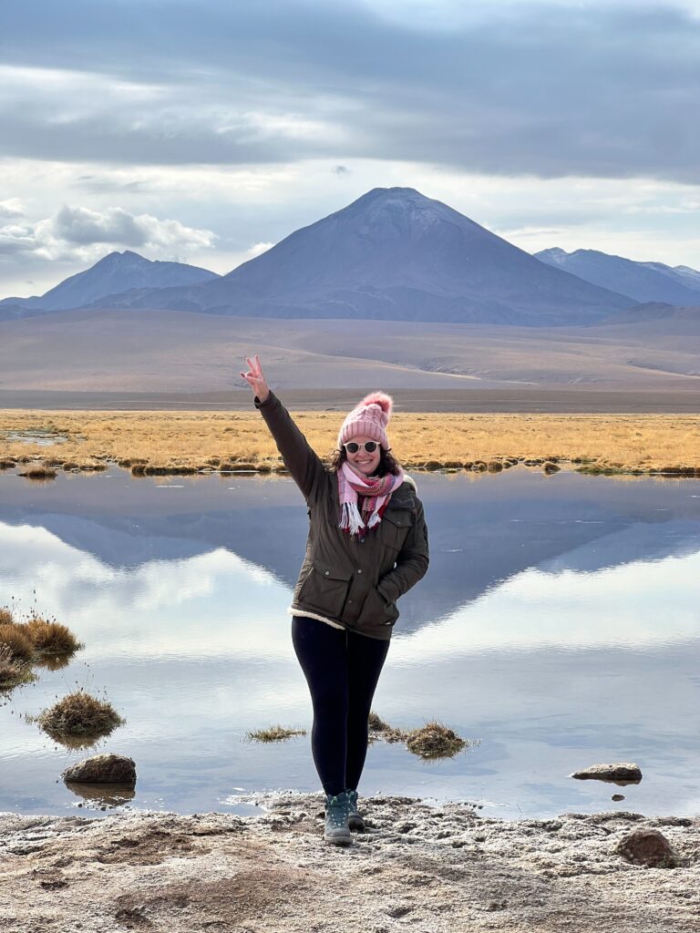Mulher em frente ao vulcão Licancabur refletido na água do Salar do Atacama, Chile