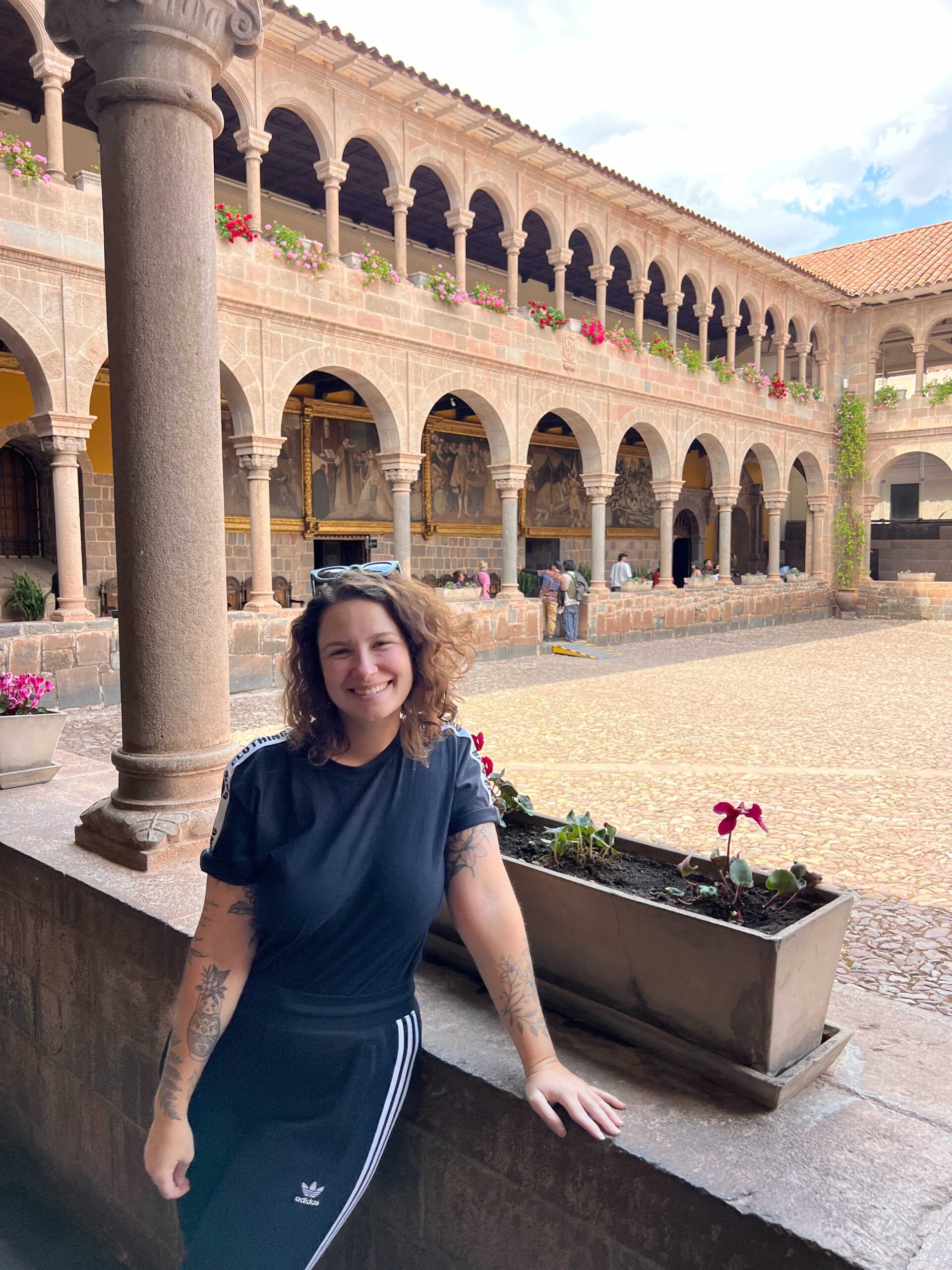Viajante sentada no claustro de arcos do Convento de Santo Domingo, construído sobre o Qorikancha, no centro de Cusco