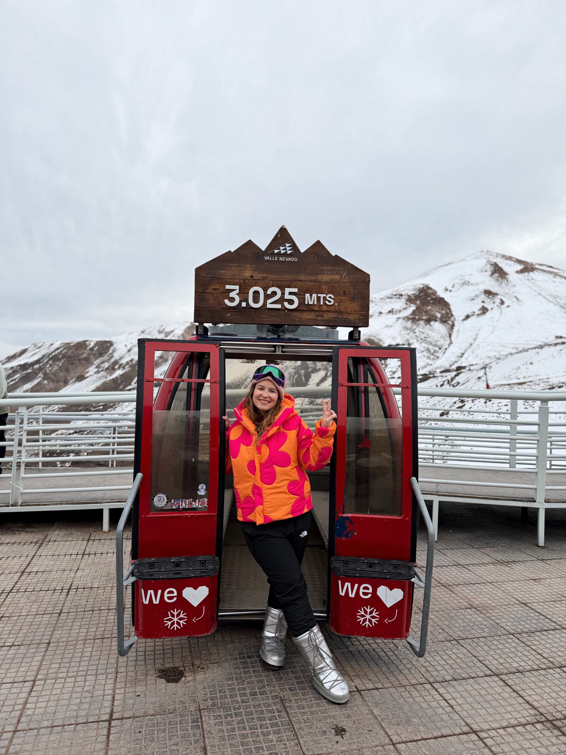 Mulher em uma cabine de gôndola no Valle Nevado, no Chile, com a placa de 3.025 metros de altitude