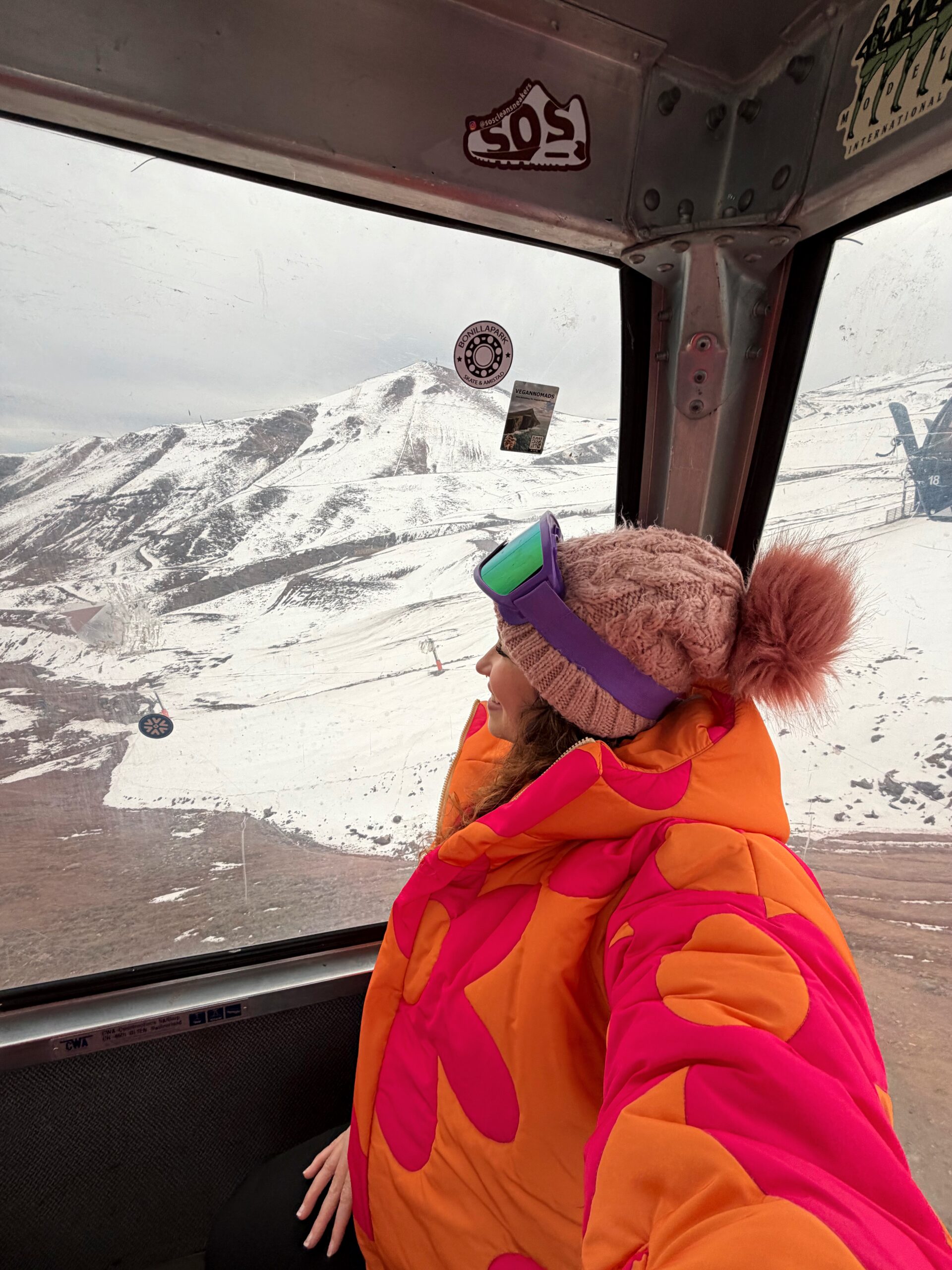 Mulher observando a montanha nevada sob a estrutura do teleférico em um parque de neve perto de Santiago do Chile