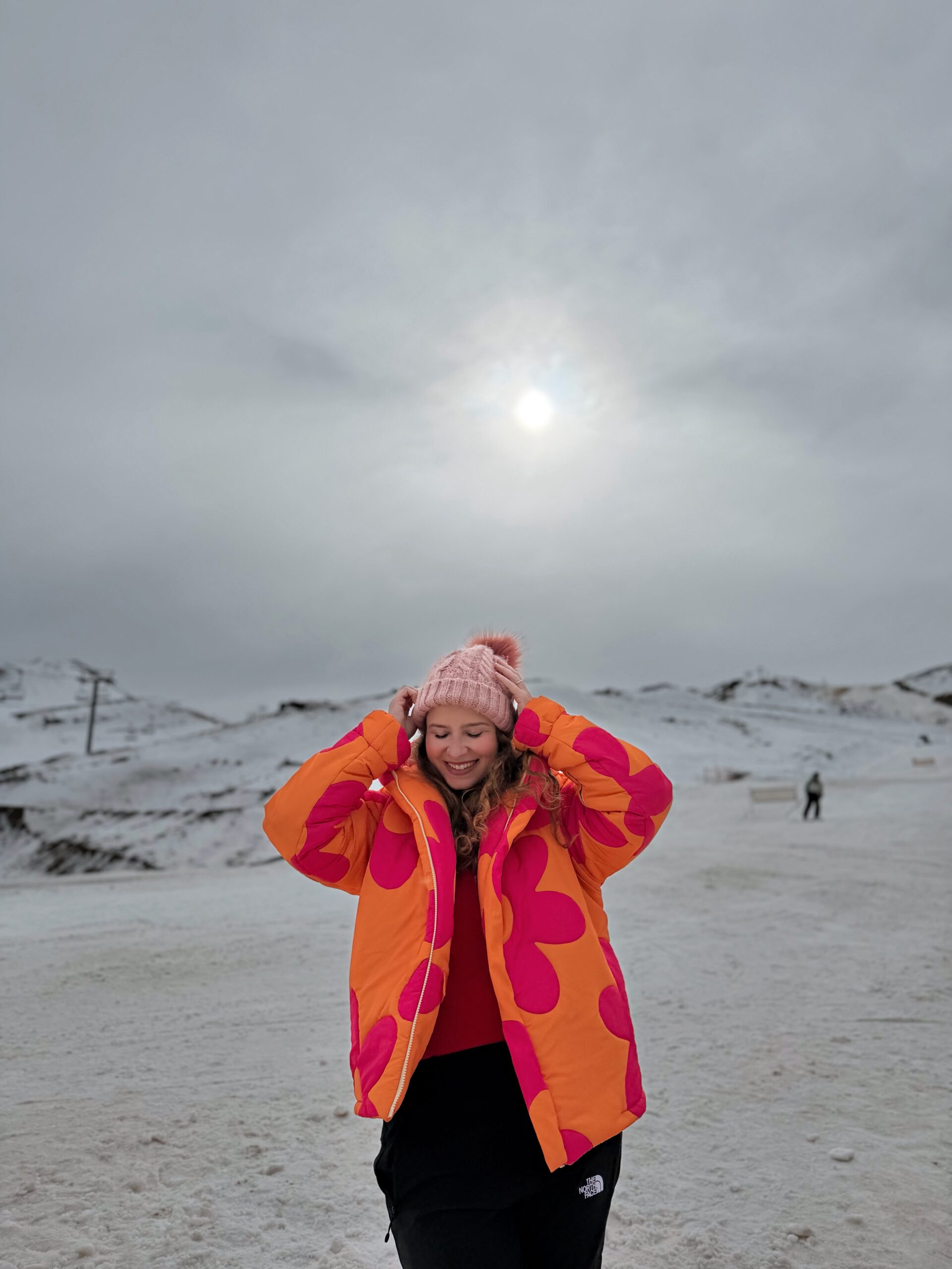 Mulher na neve do Valle Nevado, no Chile, com o sol de inverno atrás e o céu encoberto