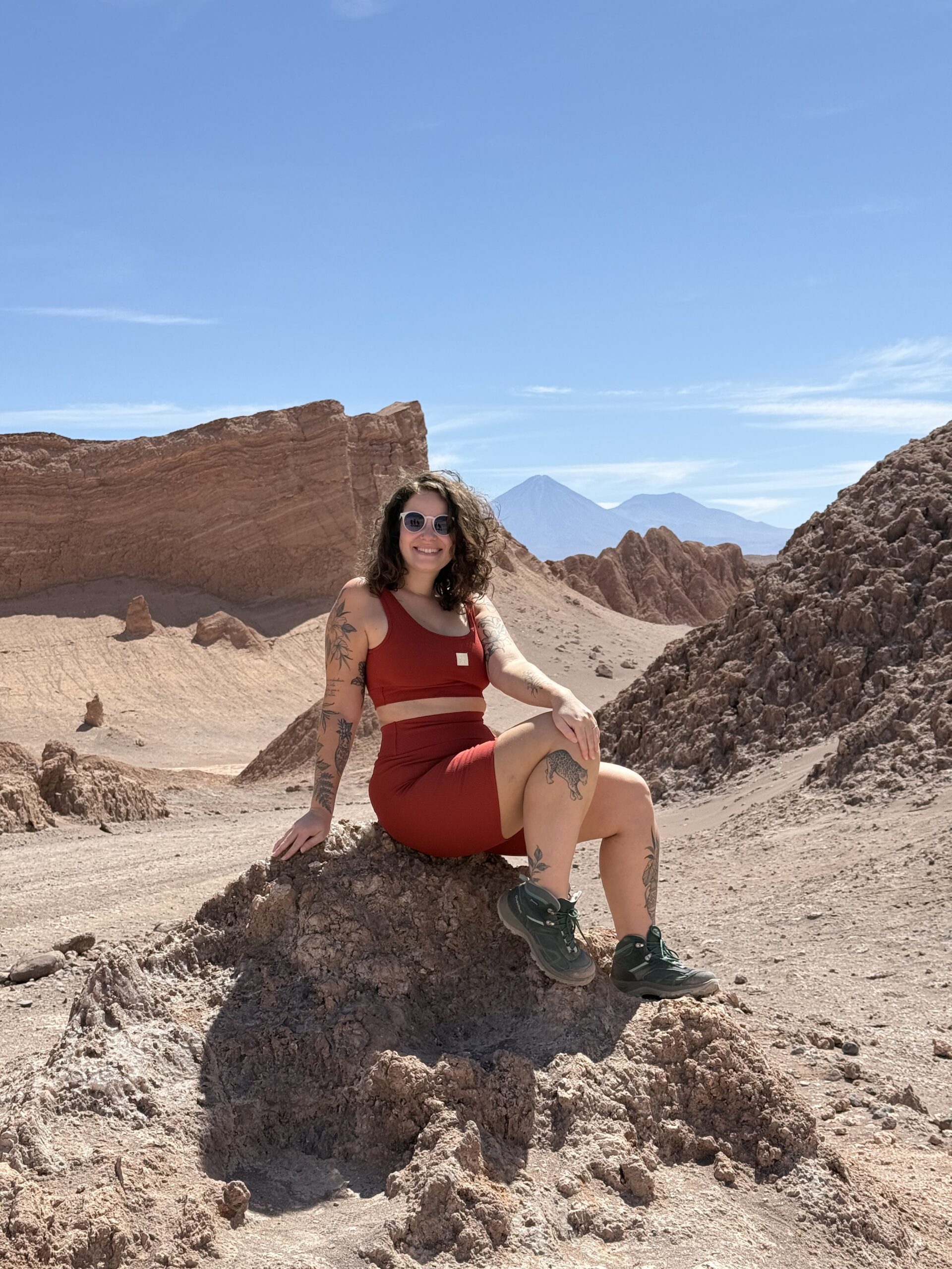 Mulher sentada em formação rochosa do Valle de la Luna, no deserto do Atacama