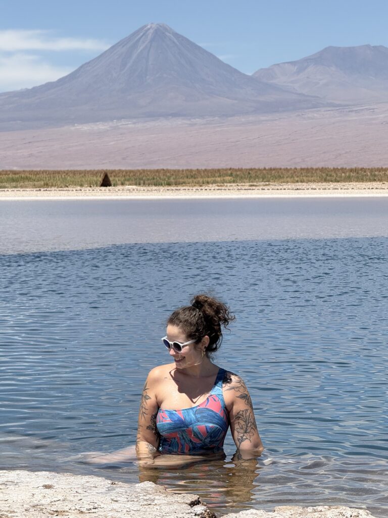 Mulher dentro da água salgada da Laguna Cejar com o vulcão Licancabur ao fundo