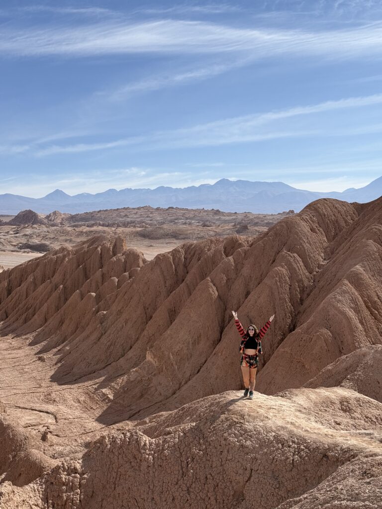 Mulher de braços abertos nas formações de areia do Valle de la Luna, Atacama
