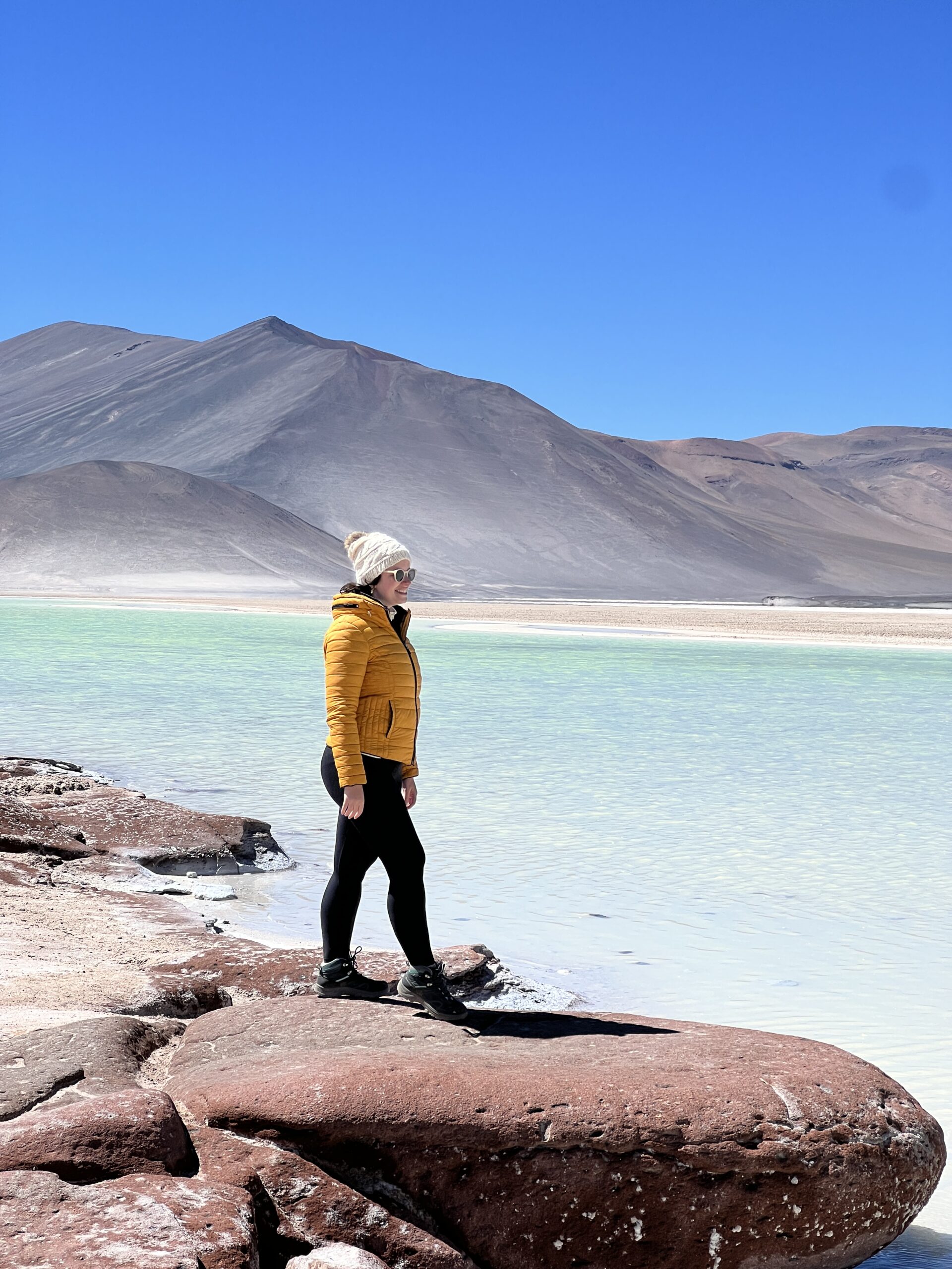 Mulher diante das águas turquesa das Piedras Rojas, no altiplano do Atacama