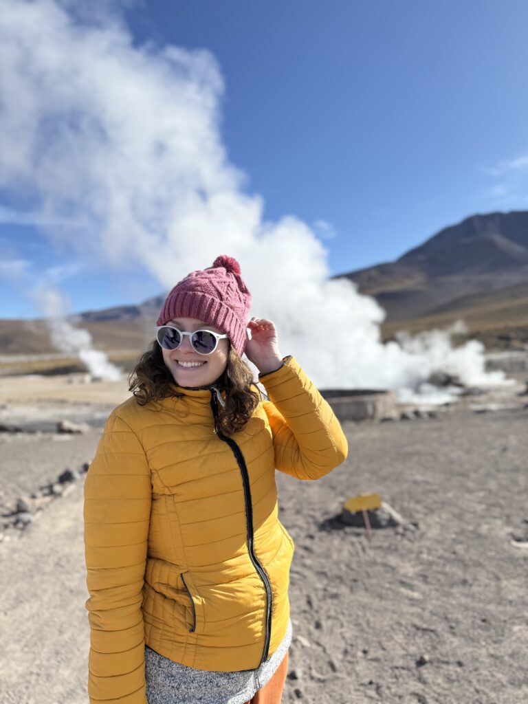 Mulher de gorro entre as fumarolas dos Geiseres del Tatio, no Atacama, ao amanhecer