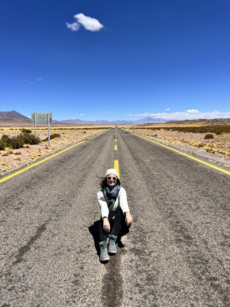 Mulher agachada no meio da estrada deserta que corta o Atacama, Chile