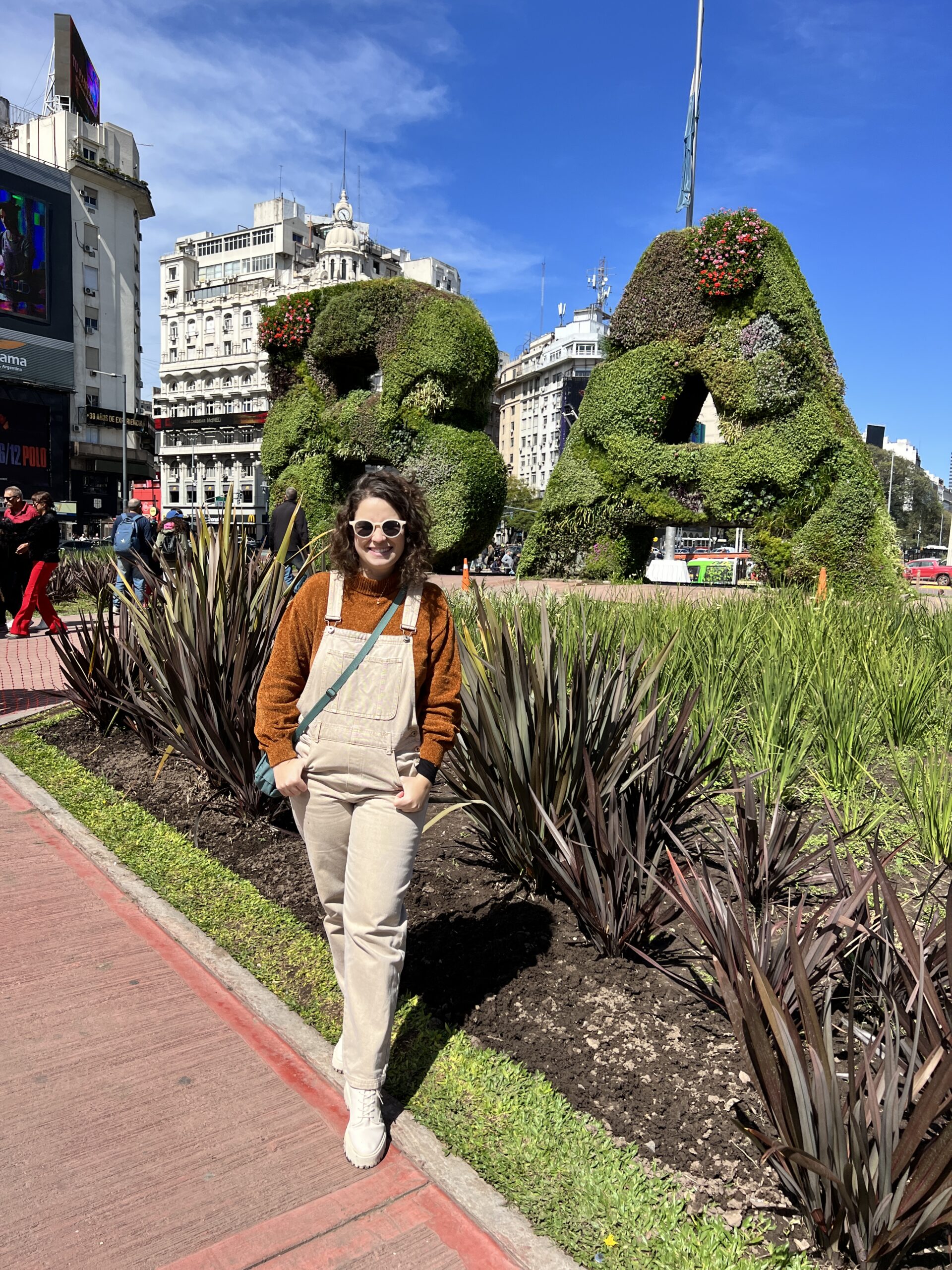 Letreiro BA em arbustos, com o Obelisco ao fundo, em Buenos Aires